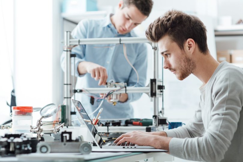 engineering students in a lab, fixing a 3D printer